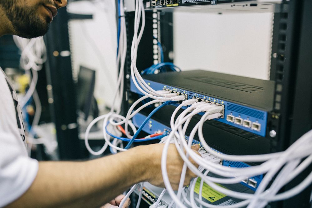 Technician Connecting Network Cables In An Equipment Rack